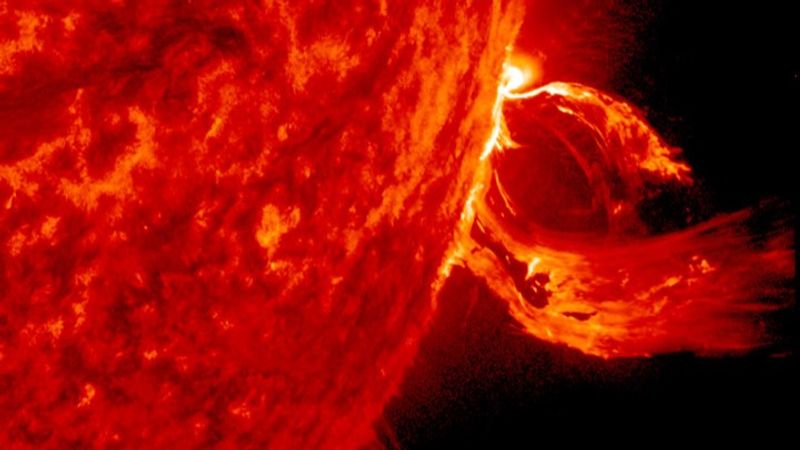 A portion of the sun and from its limp a u shaped cme stretching out like a scarf in the wind