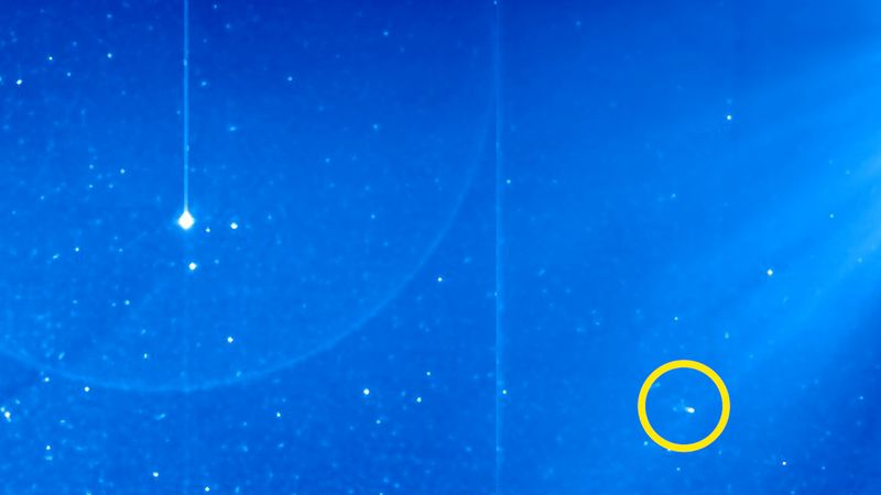 a view of the sky from space. distant stars are fuzzily visible in the distance. a bright dot - mercury - is on the left and a dimmer dot with a tail is on the right.