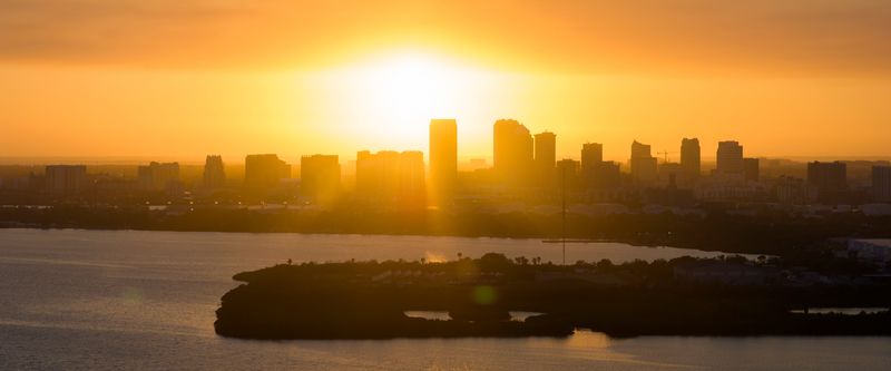 Dramatic skyline with high skyscraper buildings as the sun sets behind them in an explosion of orange