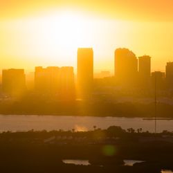 Dramatic skyline with high skyscraper buildings as the sun sets behind them in an explosion of orange