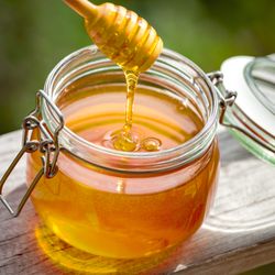 Honey in glass jar on a wooden floor.