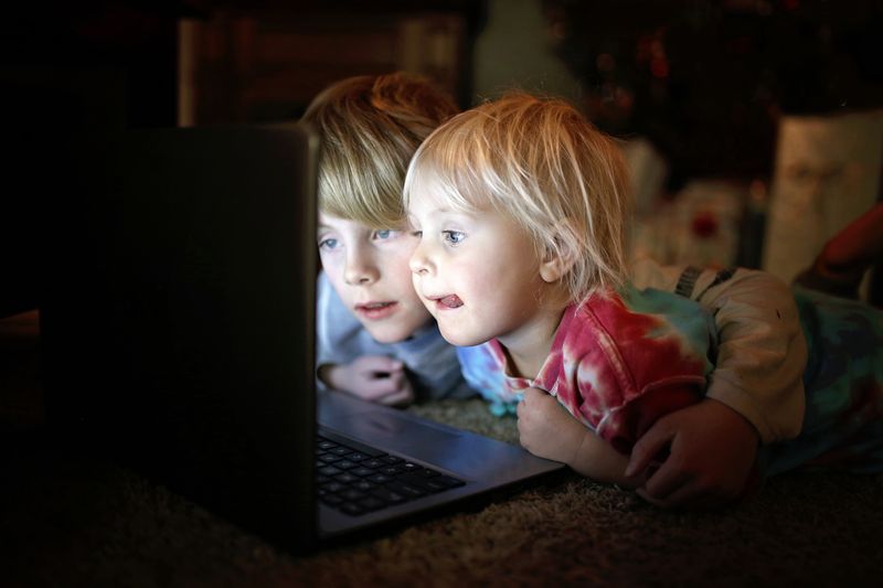 two kids watching a something on a laptop together