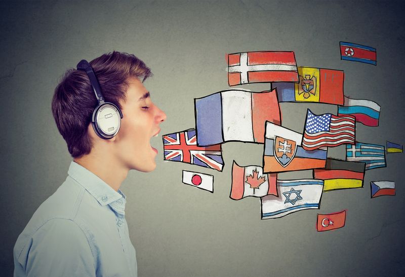 man wearing headphones with mouth open as if speaking, with illustrated flags from different nations to represent multiple languages
