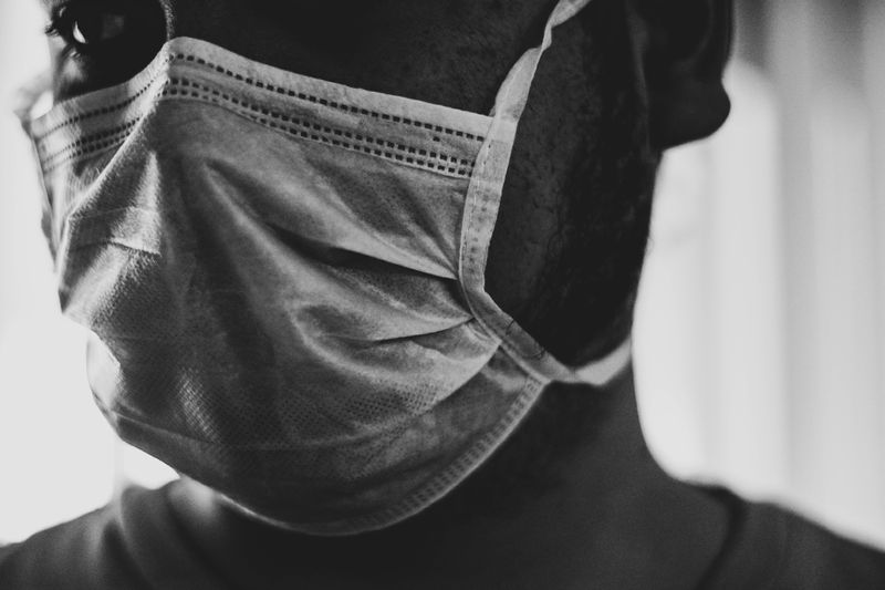 black and white close up photo of person wearing a white disposable mask