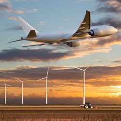 Plane takes off above a farm field and wind electric generators