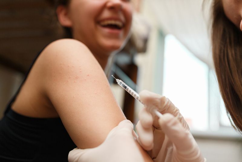 A girl receives a polio vaccine from a nurse wearing surgical gloves