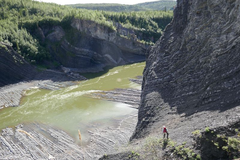 A geologist looks down at exposed Ordovician (approximately 475 million years ago) chert and shale of the Mount Hare Formation, Road River Group, on the Peel River, Yukon.