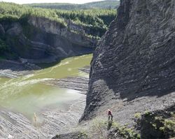 A geologist looks down at exposed Ordovician (approximately 475 million years ago) chert and shale of the Mount Hare Formation, Road River Group, on the Peel River, Yukon.