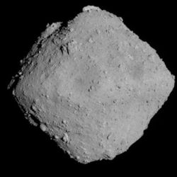 the asteroid is a grey rhombus against the black of space. it is has a rough surface with several boulders visible on it.