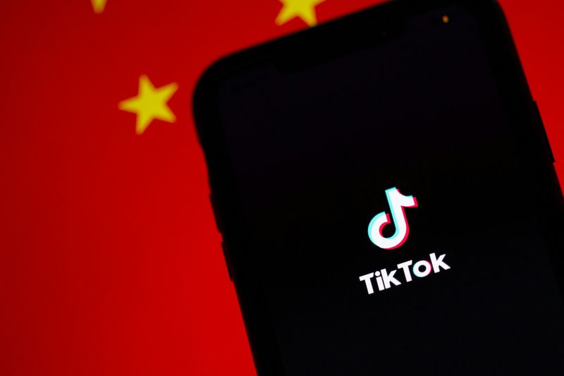 A smartphone showing the TikTok social media app in front of a red flag of Chna