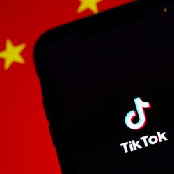 A smartphone showing the TikTok social media app in front of a red flag of Chna