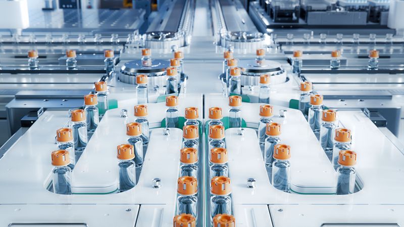 production line with lots of medical vials with orange lids on a conveyor belt