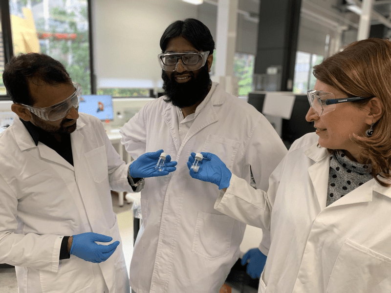 Dr Nasir Mahmood, PhD candidate Muhammad Haris and Professor Nicky Eshtiaghi (left to right) with a sample of water with microplastics and a vial of clean water following its treatment with their innovation. 