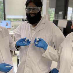 Dr Nasir Mahmood, PhD candidate Muhammad Haris and Professor Nicky Eshtiaghi (left to right) with a sample of water with microplastics and a vial of clean water following its treatment with their innovation. 