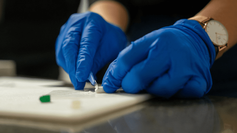 A sample of some clumped powder is taken for testing at the CanTEST facility