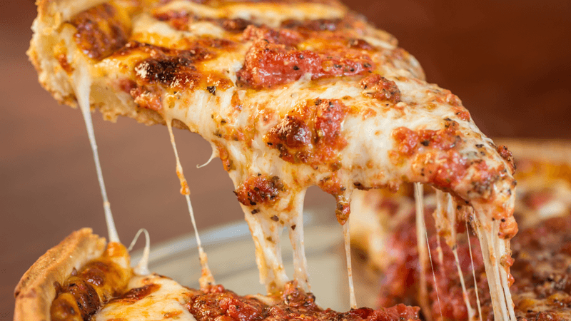 a slice of pizza with melted cheese oozing of the edges