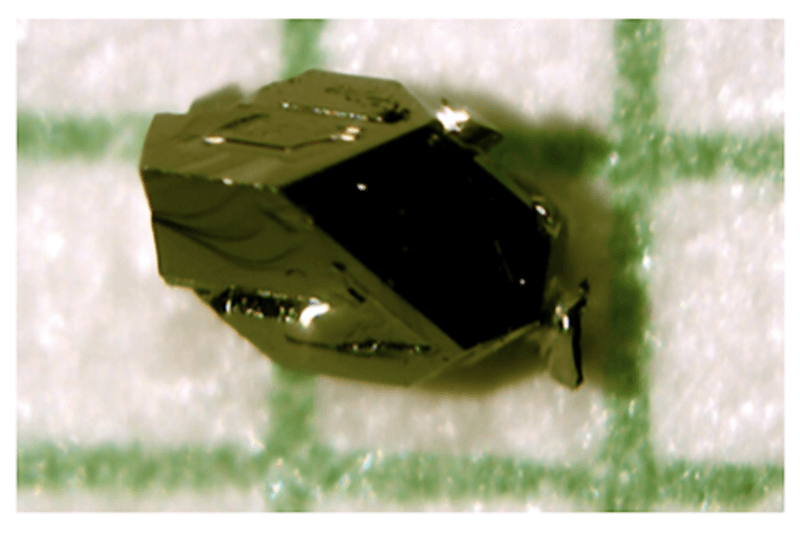 a dark green crystail is seen over a reticulate paper