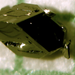 a dark green crystail is seen over a reticulate paper