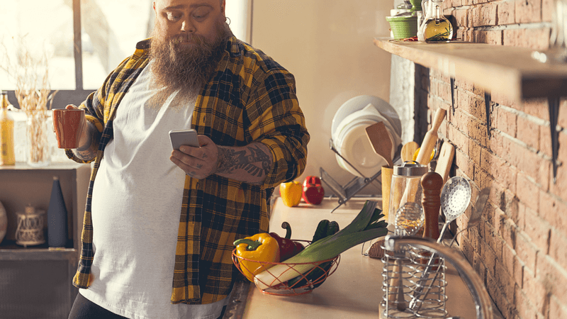 man looking at encouraging text message in his kitchen