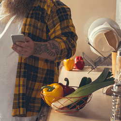 man looking at encouraging text message in his kitchen