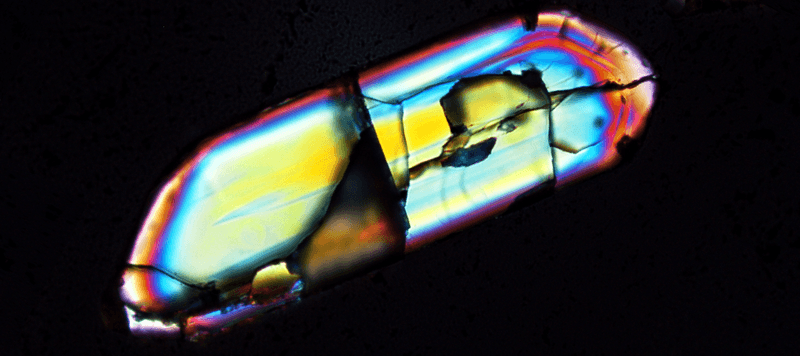 A zircon grain (0.250 mm by 0.070 mm, approximately the width of a human hair). These are the oldest minerals on Earth and provide crucial insight into the early Earth.